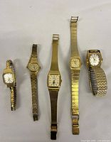 All five gold-tone ladies' wristwatches laid out side by side