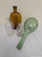 Group shot of four antique bottles: two clear Listerine, one amber, one pale green long-neck