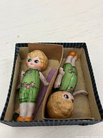 Pair of bisque porcelain dolls in original striped cardboard box showing outfits, size and condition