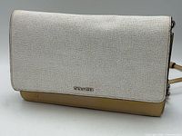 Front view of Coach foldover clutch showing textured off-white flap and tan base