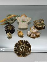 Group shot of all nine brooches on mirrored surface