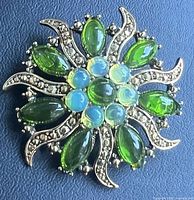 Front view of brooch showing green rhinestones and clear accent stones