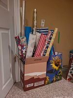 Box containing multiple wrapping paper rolls, cellophane roll and gift bags