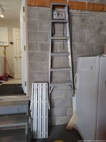 Ladder and plank leaning against wall for size reference
