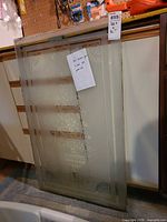 Full view of two stacked etched glass panels leaning against cabinet