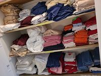 Multiple shelves holding folded towels, washcloths, sheets, quilted pad