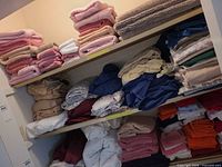 Shelves with multiple stacks of folded bedding in various colours and patterns