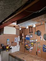 Pegboard wall with assorted packaged hardware, tape rolls, paint brushes and bungee cords