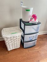 All three items: Sterilite cart, trash bin on top, wicker hamper beside