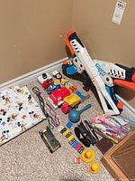 Wide shot of all items including blaster, vehicles, beads, dominoes, pens, sunglasses and duck