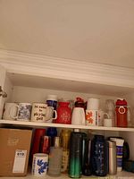 Cabinet shelves showing majority of bottles and mugs