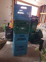Stack of five plastic milk crates, blue and green, overall view