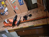 Full view of hedge trimmer on workbench with battery and charger