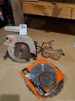 Circular saw, spare blades in packaging, safety goggles