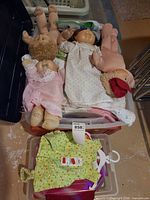 Bin containing four Cabbage Patch Kids dolls and loose clothing