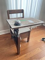 Front view of child-size oak school desk with bell on desktop