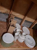 Group view showing casserole, stacks of plates, mugs and boxed flatware