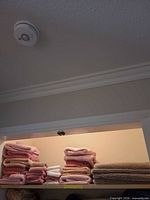 Stacked pink, white and beige towels on shelf
