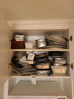 cabinet shelves loaded with foil pans, plastic containers, wicker basket