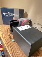 DVD box set, two speakers, stack of audio CDs visible together on shelf