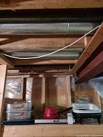 All three electric cookware pieces on shelf: aluminum griddle (stacked), red saucepan and white/black skillet