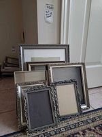 Group of silver-tone ornate frames stacked and leaning, shows size range and quantity