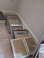 Stack of assorted metal frames along wall, showing variety of sizes and styles