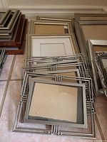 Stacks of assorted frames on floor showing metal, wood, ornate types