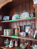 overview of lot on shelving showing tumblers, stein, glasses, candle holder, frame, snow globes and figurines