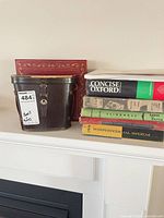 Binocular case and stack of six vintage hardcover books on mantel