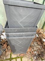 Two stacked tall slate gray Hampton Bay planters showing exterior condition