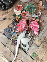 Pile of assorted metal garden decor pieces on wooden floor