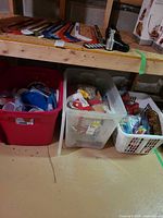 Overview of red tote, clear tote, laundry basket under shelf with party supplies and ornaments visible