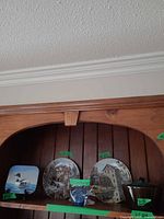 Full lot on shelf showing plate, second plate, fish paperweight, loon tile, pot