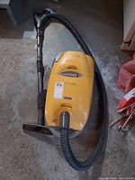 Kenmore yellow and gray canister vacuum with attached hose and wand on floor