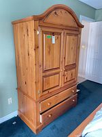 Full front view of knotty pine armoire with doors and drawers closed