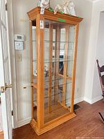 full view of light oak curio cabinet with glass panels and shelves