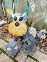 Group view of metal dog stake and three resin owl statues on patio