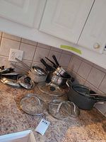 Group view of saucepans, stockpot, lids, and steamer insert on countertop