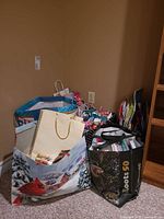 Shopping bags filled with various gift wrap supplies and cards stacked in corner
