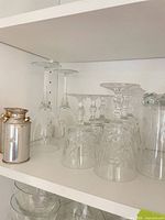 Shelf with various clear stemmed and cut crystal glasses plus metal canisters