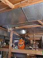 Shelf view showing large jack-o’-lantern, ghost holder, witch figure, skeleton figurines