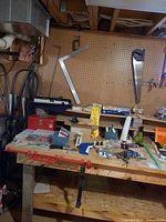 Workbench with framing square, bar clamp, toolbox and assorted hardware visible