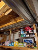Shelf with multiple LED bulb cartons, bath tissue package, trash bags, tissues, Lysol wipes, Behr paint