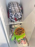 Stacked dish towels, pot holders on shelves