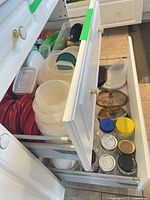 Drawer of stacked plastic food containers with assorted lids