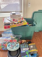 Overview of lot showing tote, Rummoli game, Lineup game, electronic disc game, loose toy bags