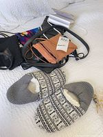 Group view of slippers, black evening clutch, tan crossbody bag, additional black strap