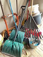 Overall lot showing dolly, two snow shovels, leaf rake, broom, buckets