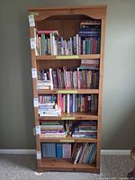 Front view showing full height, wood grain, five shelves filled with books (books not included)